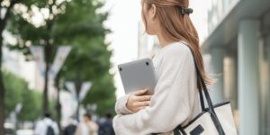 通学時にノートパソコンを持ち運ぶ女子大学生の様子