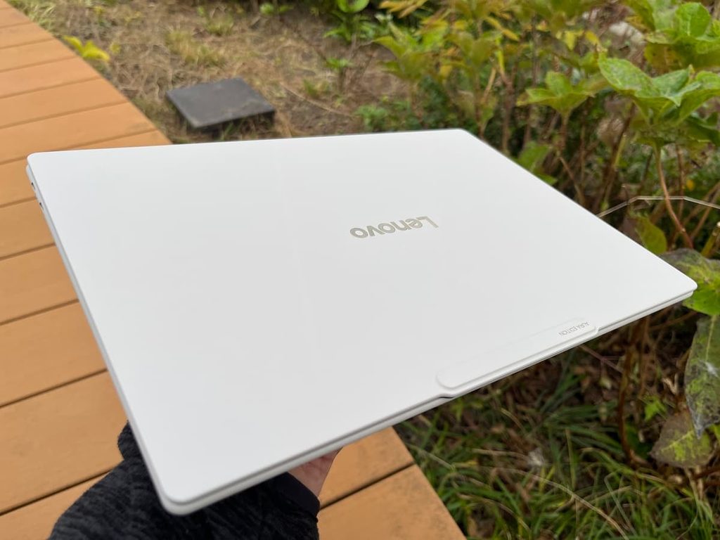 Yoga Slim 7i Ultra Gen 11 Aura Editionを屋外で片手で持ち上げた様子